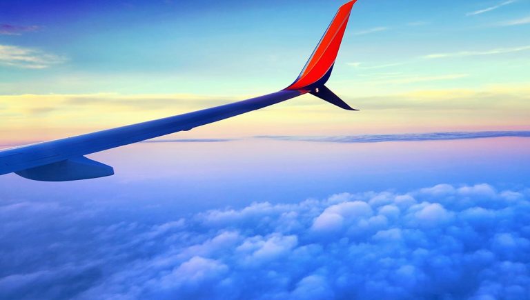 Avion volando sobre nubes - vista del ala desde la ventana